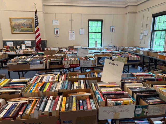 Many books piled on top of tables in the library book sale